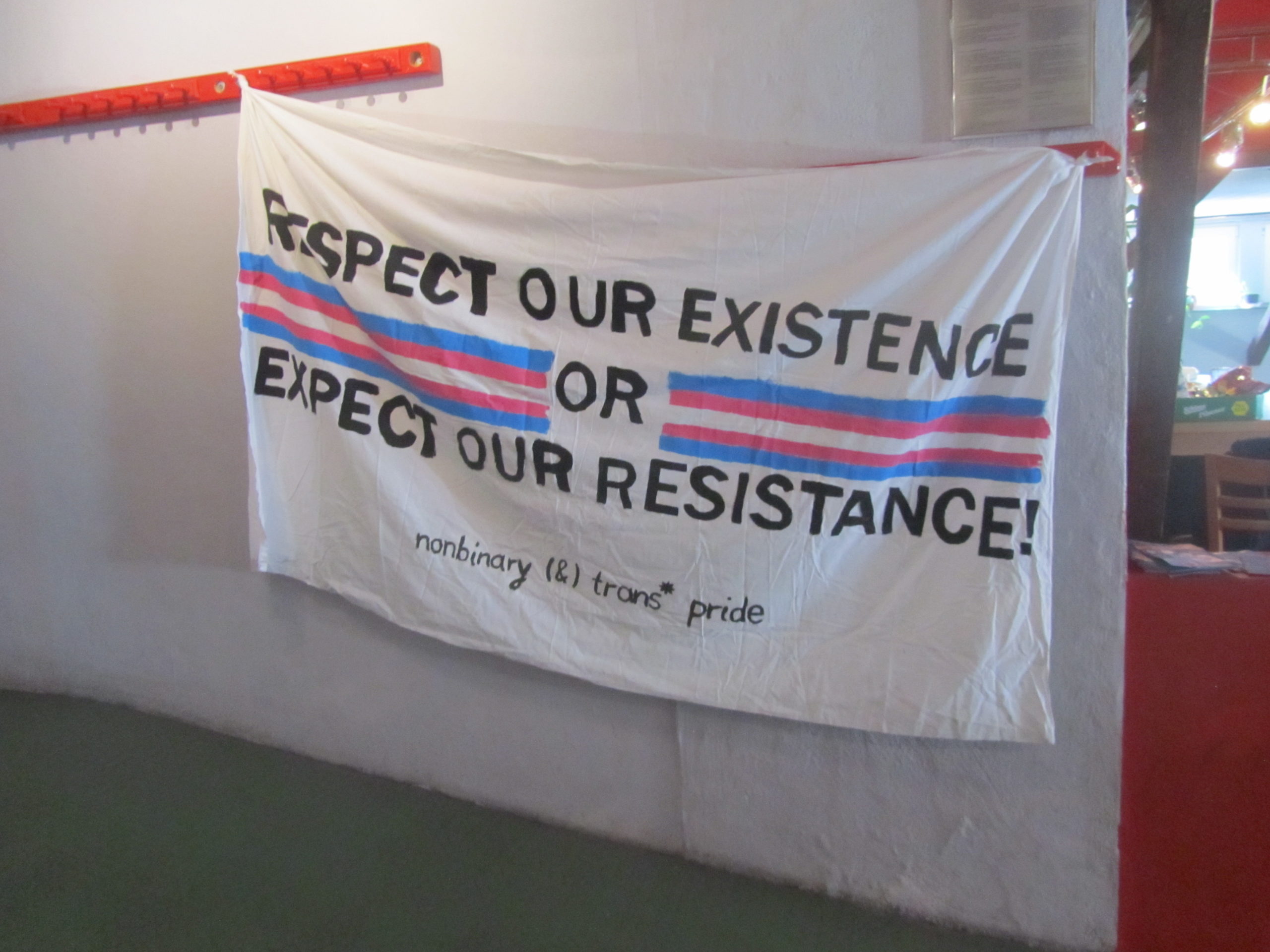 Banner auf der Trans*Tagung mit der Beschriftung "Respect our Existence or Expect Resistance!" - "nonbinary (&) trans* pride"
